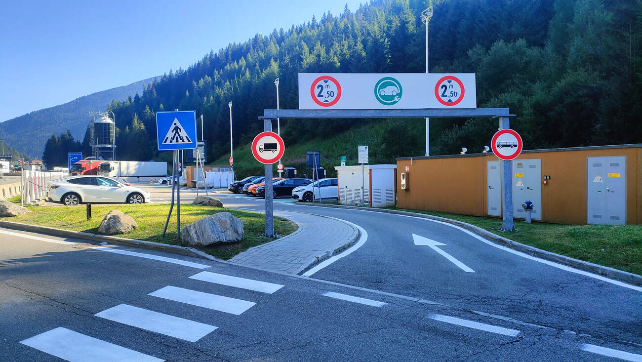 Zufahrt zur Ladezone am Brenner mit Hinweisschild 2,50 m Durchfahrtshöhe, mehrere E-Autos parken bereits