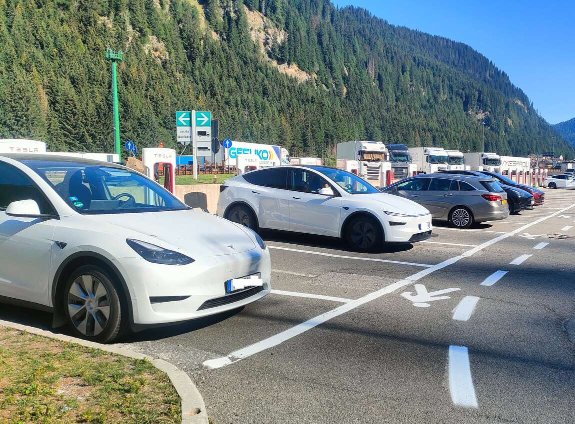 Mehrere Tesla-Fahrzeuge an den Tesla-Ladesäulen am Brenner, im Hintergrund Berge